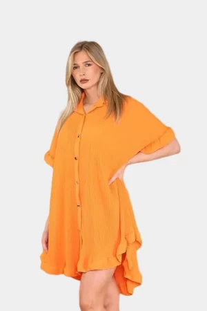 Woman posing in orange colored casual loose fit frill hem mini button down summer dress against solid grey background