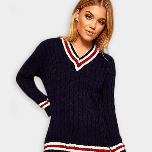 A beautiful blonde hair woman wearing stripe V neck cable knitted cricket jumper in navy color against solid grey background